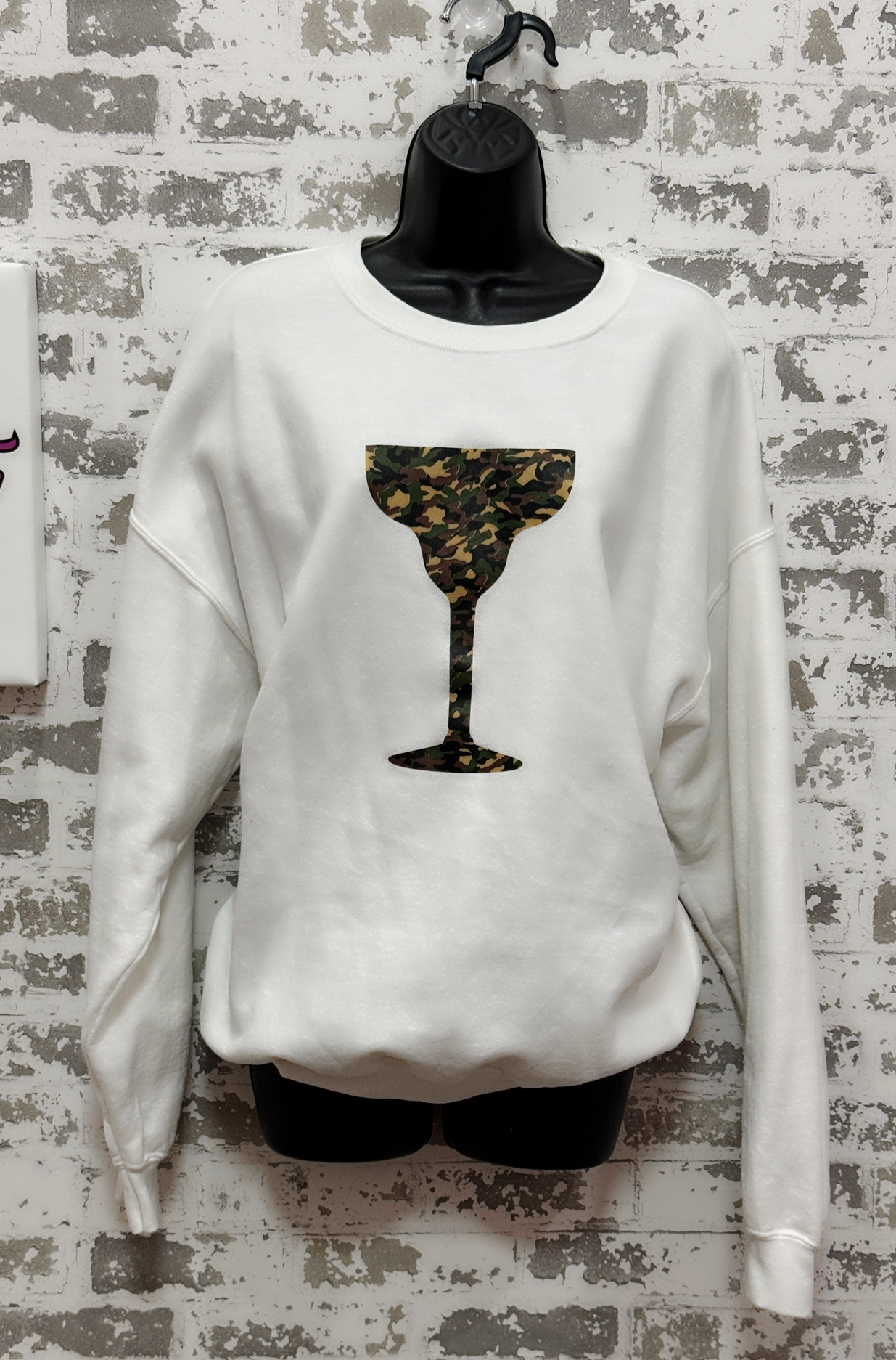 White sweatshirt with a black and gold abstract design on a textured wall background