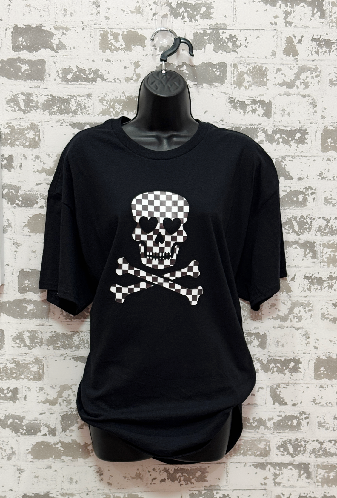 Black t-shirt with a skull and crossbones design on a textured wall background