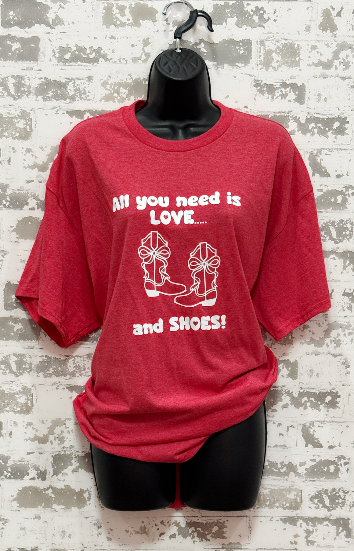 Red t-shirt with white text and graphics on a mannequin against a textured wall background