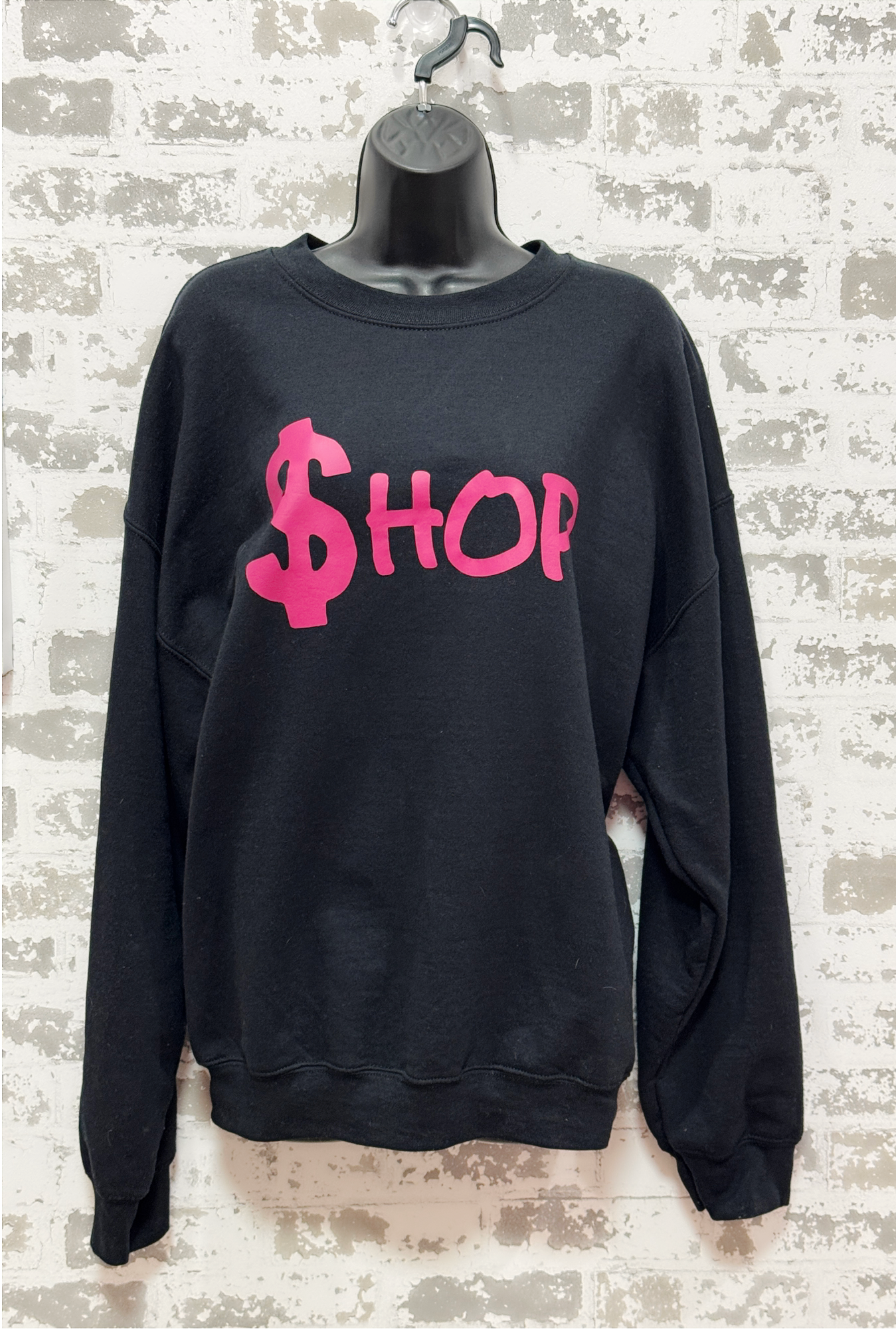 Black sweatshirt with pink text on a textured wall background