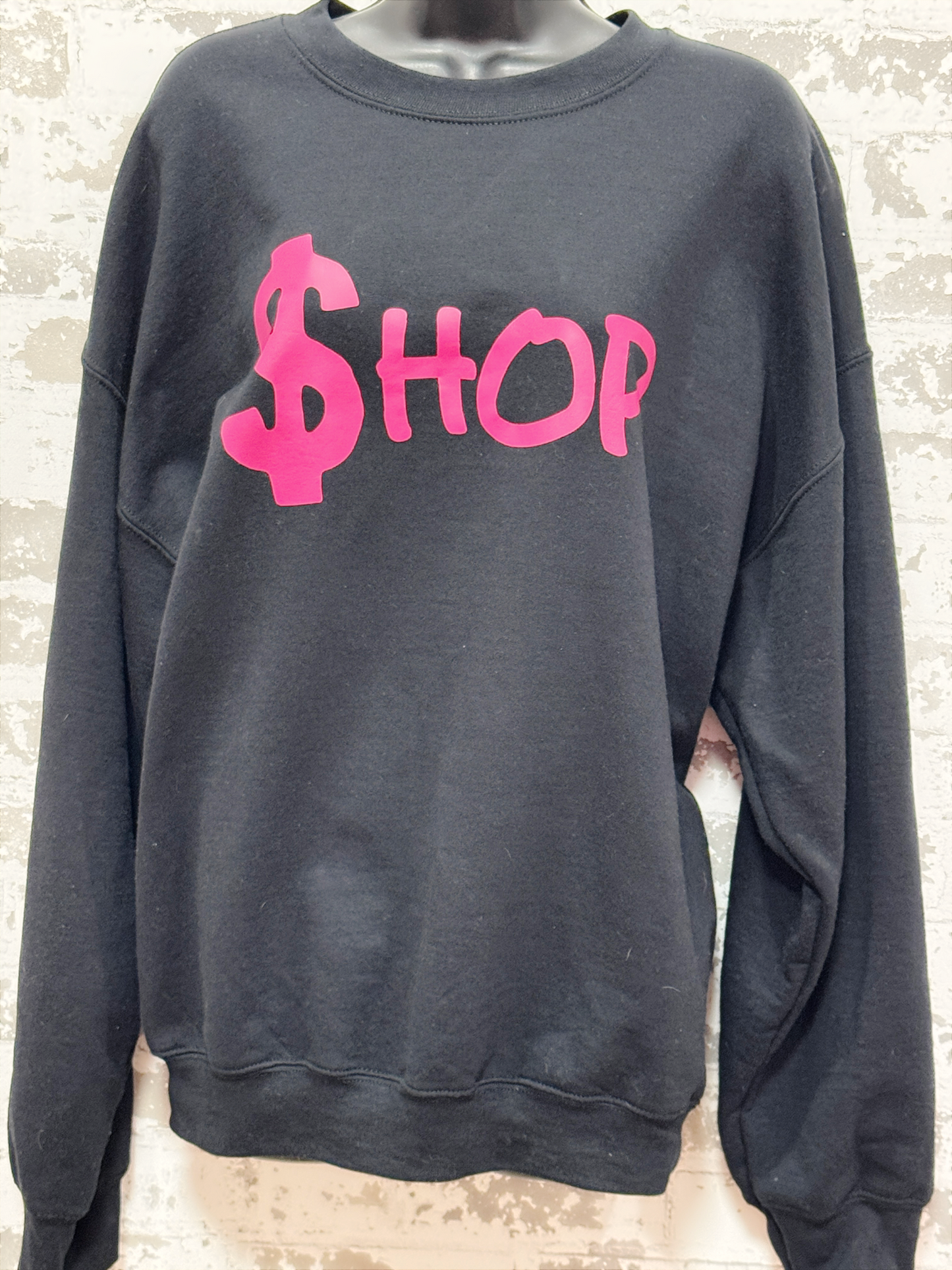 Black sweatshirt with pink text on a textured white background