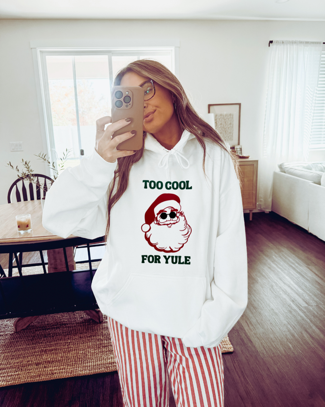 Person wearing a white hoodie with a Santa Claus graphic and text, standing in a room.