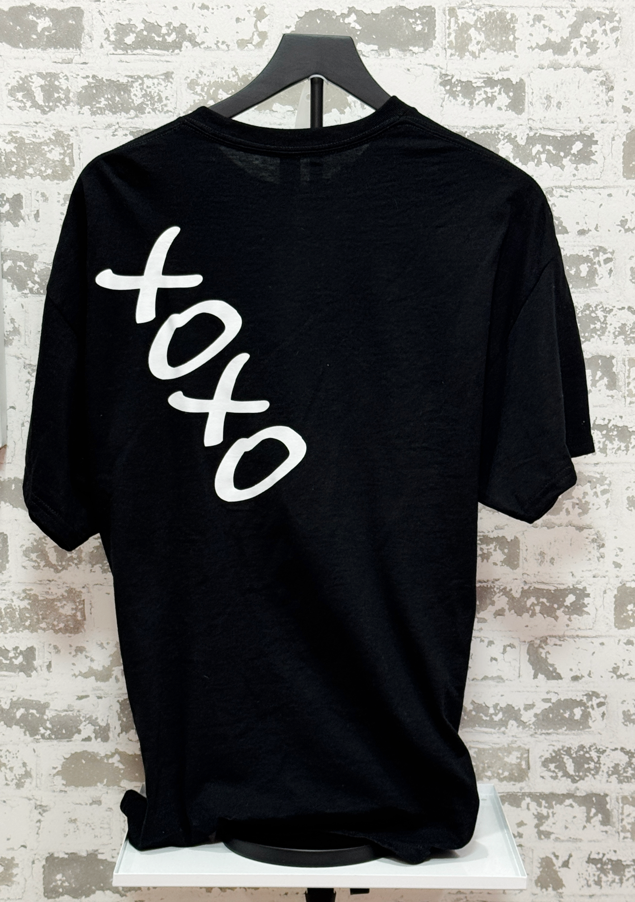 Black t-shirt with 'xoxo' text on a textured wall background