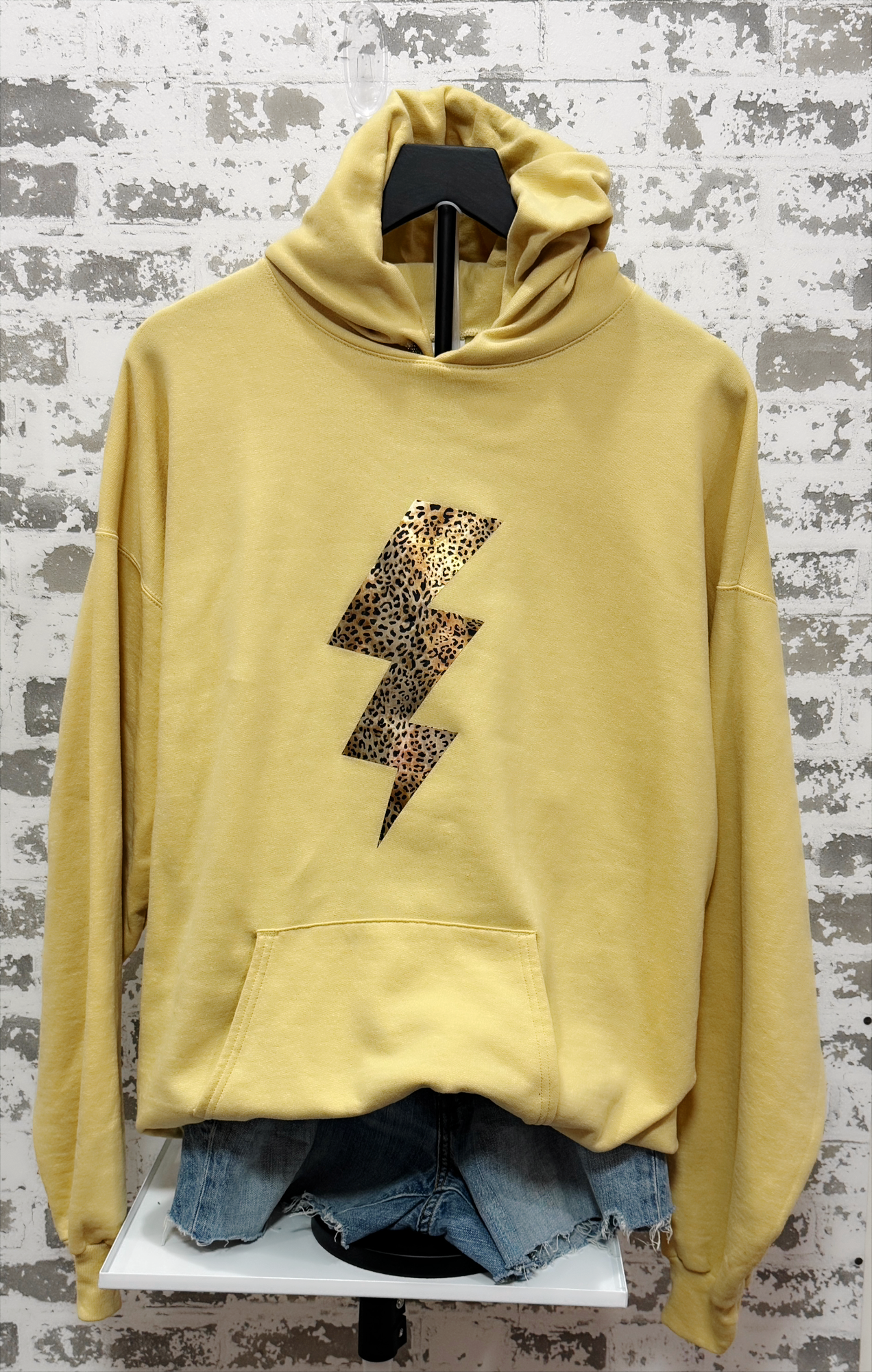 Yellow hoodie with a leopard print lightning bolt design on a gray textured background