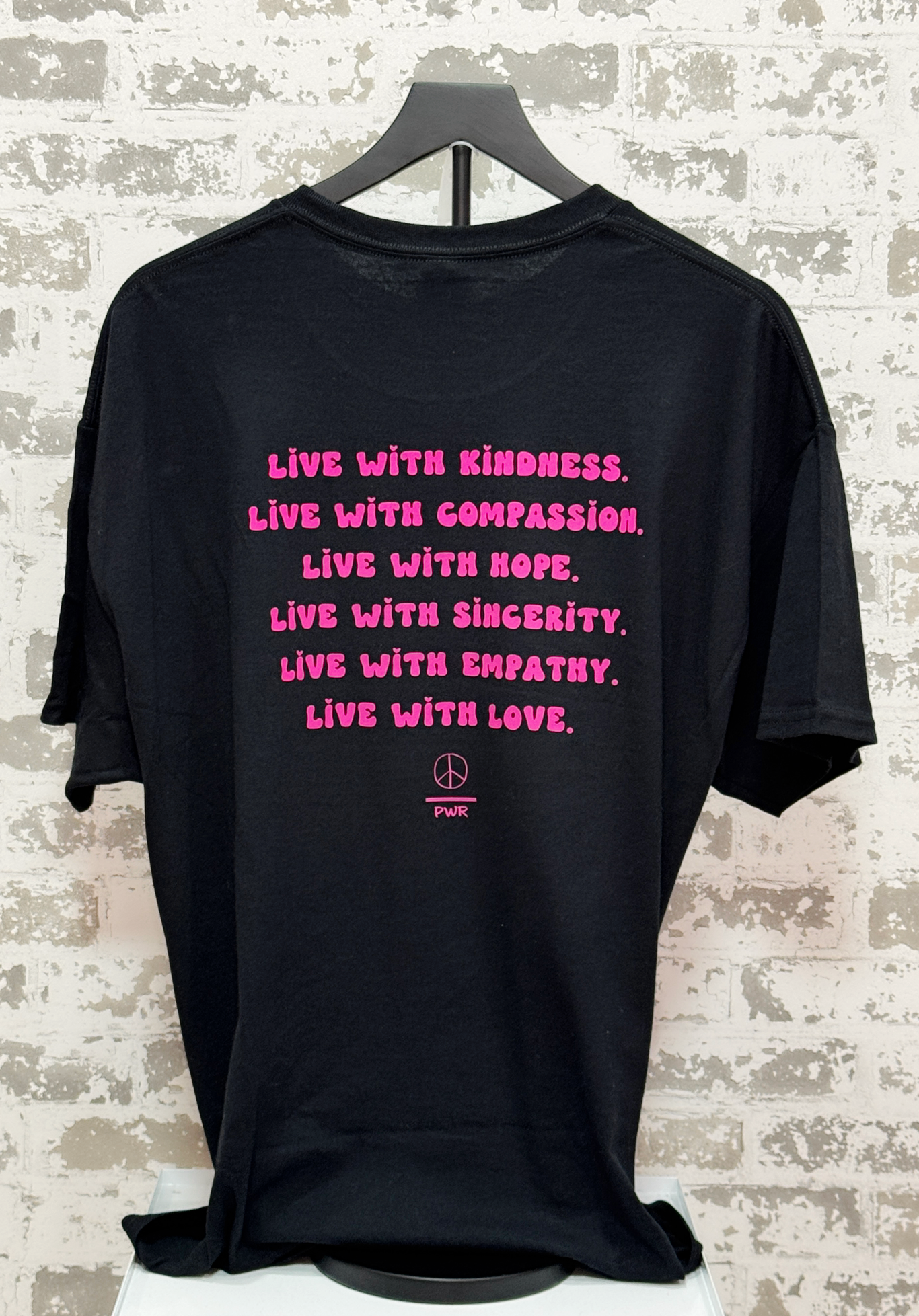 Black t-shirt with pink motivational quote on a textured wall background