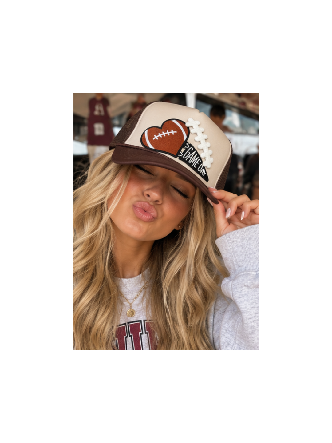 A cream and chocolate brown trucker hat featuring an embroidered football-heart patch with lace detailing and a GAME DAY pennant, captured in a high-quality product shot for The Maximalist Boutique.