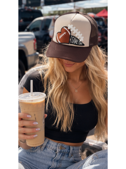 Cream and chocolate brown high-crown trucker hat featuring an embroidered football-heart patch and a GAME DAY pennant emblem, styled with dimensional lace details.