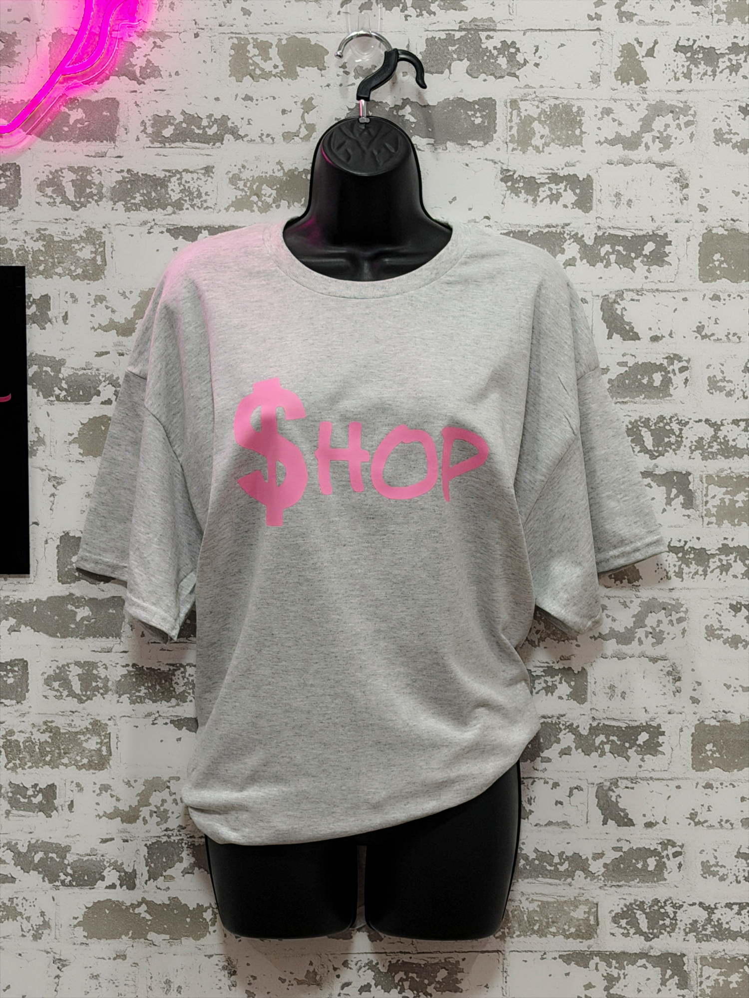 Gray t-shirt with pink text on a textured wall background