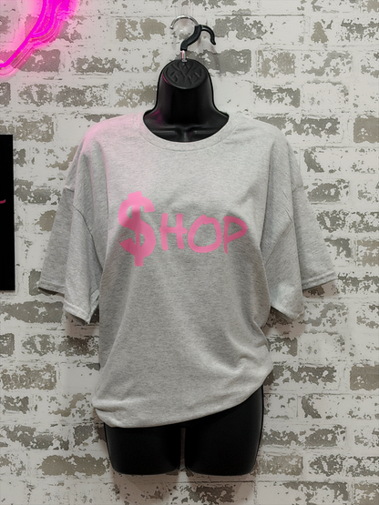 Gray t-shirt with pink text on a textured wall background