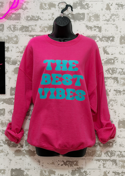 Pink sweatshirt with 'THE BEST VIBES' text on a textured white background