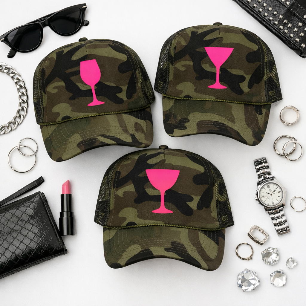 Camouflage baseball caps with pink wine glass designs, surrounded by accessories on a white background