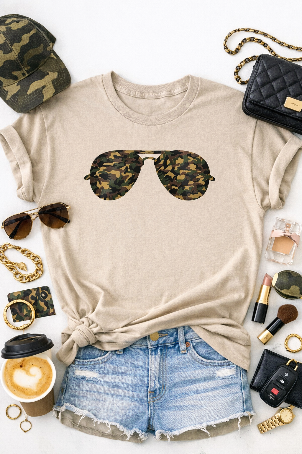 Beige t-shirt with camouflage sunglasses graphic, paired with denim shorts and surrounded by accessories on a white background.