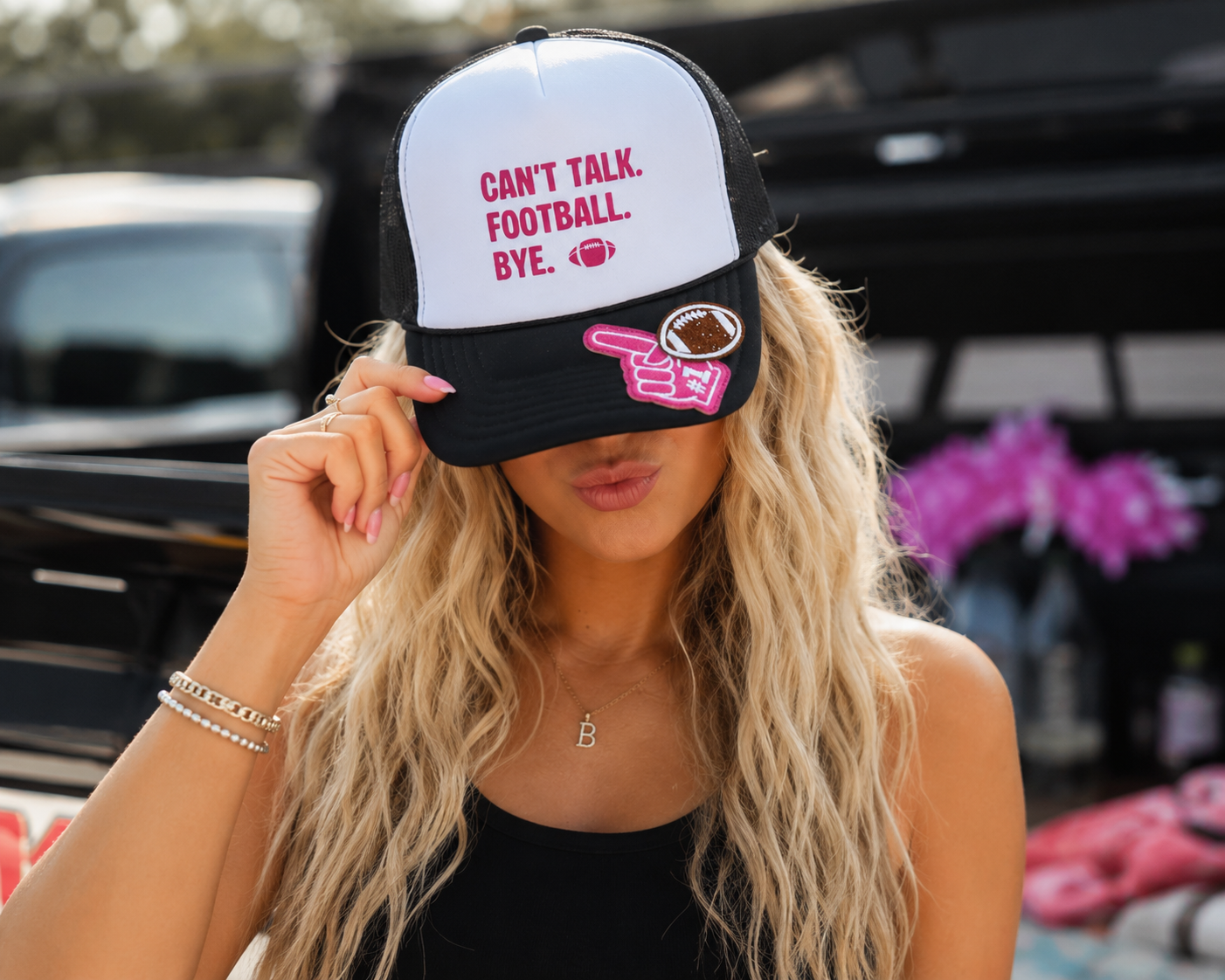 A woman wearing a white and black trucker hat with the text 'CAN'T TALK. FOOTBALL. BYE.