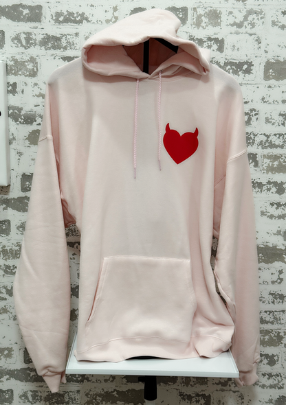 Pink hoodie with a red heart design on a textured wall background
