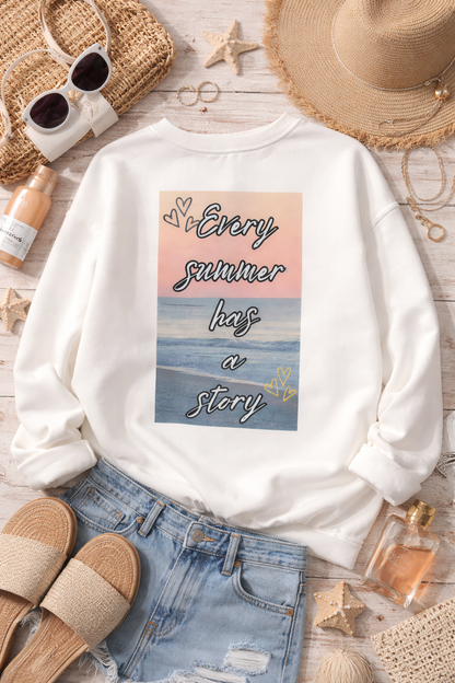 White sweatshirt with a beach-themed design and text, surrounded by summer accessories on a wooden surface.