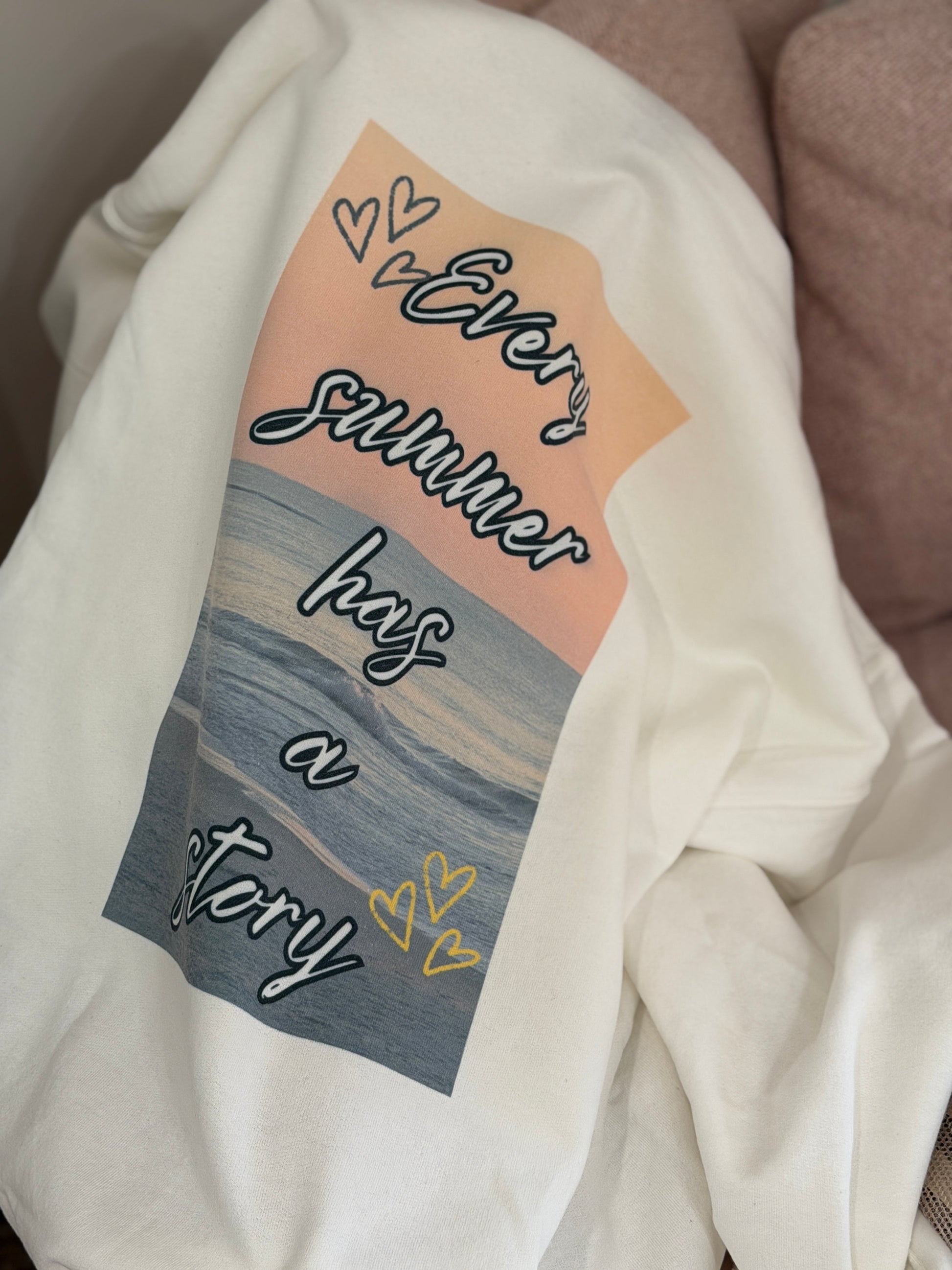 White sweatshirt with a graphic design featuring text and a beach scene.