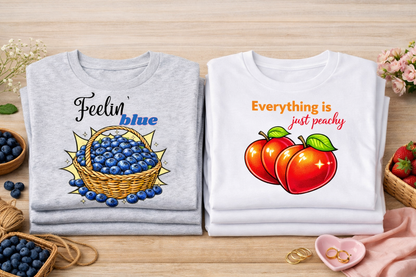 Two shirts with fruit-themed designs on a wooden surface.