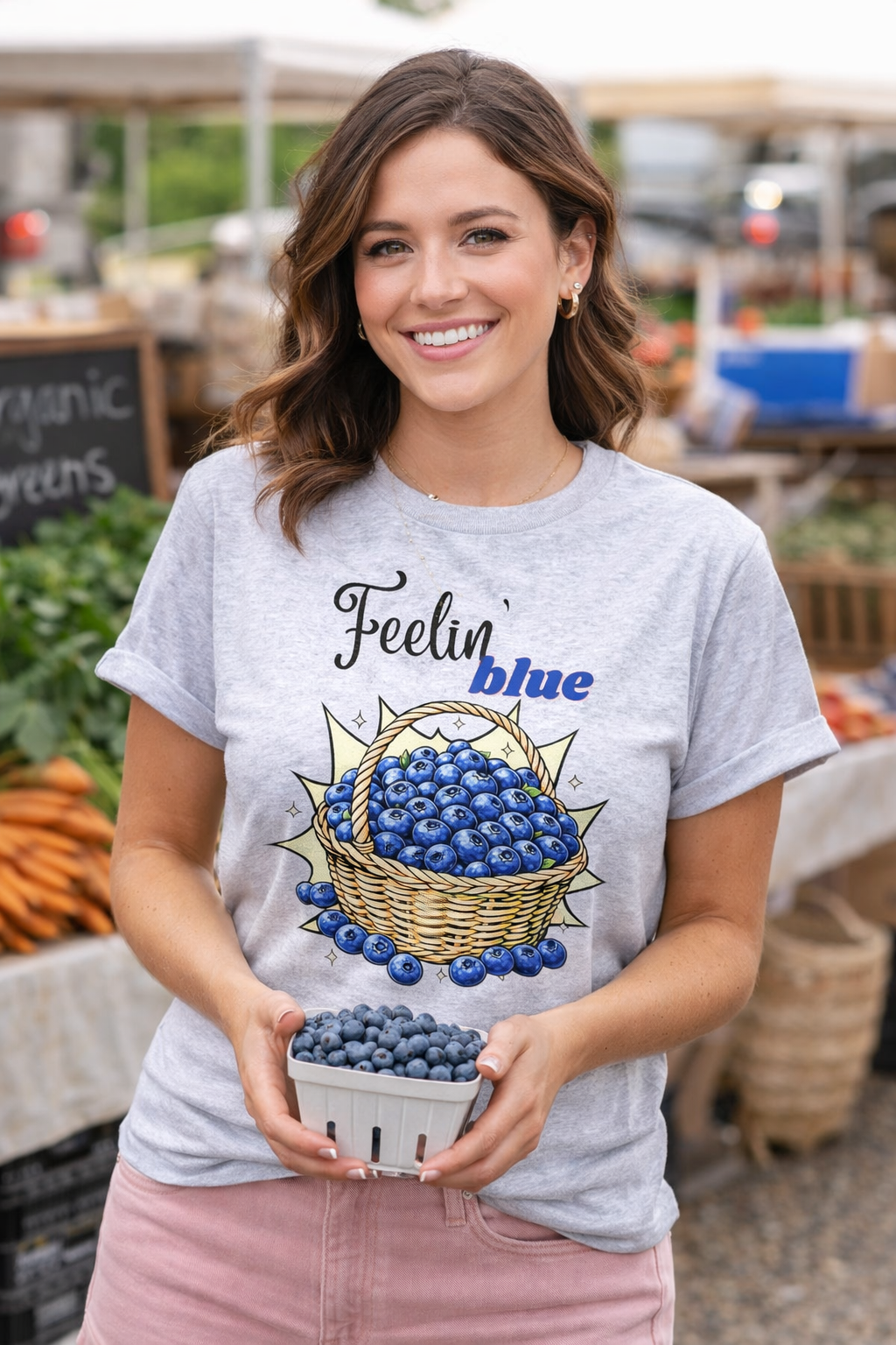 Woman wearing a t-shirt with a blueberry graphic and 'Feelin blue' text at an outdoor market.