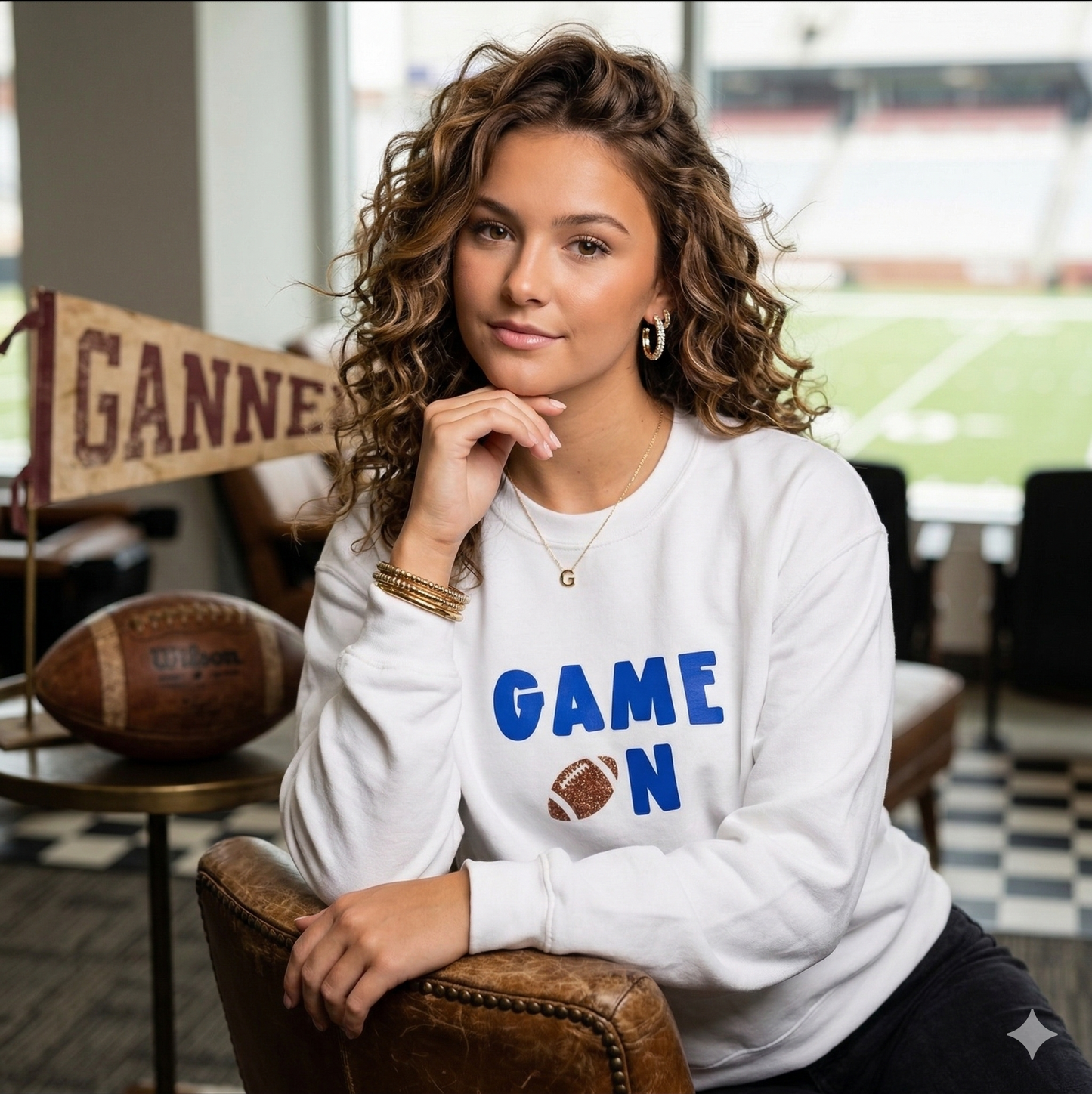 Woman wearing a white sweatshirt with 'GAME ON' text, sitting in a casual setting.