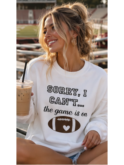Woman wearing a sweatshirt with a football graphic and text, holding a coffee in a stadium.