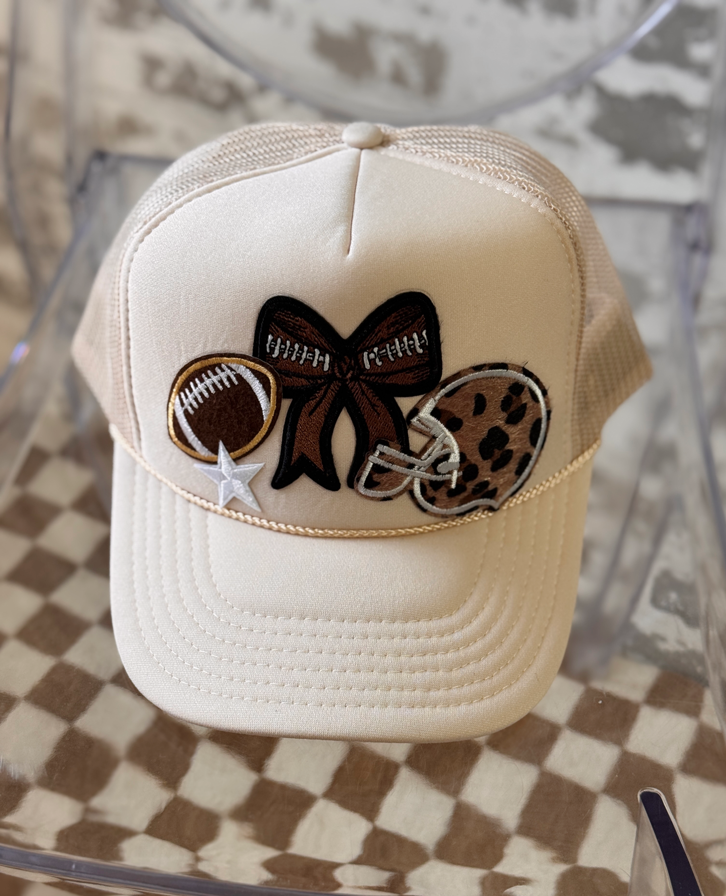 Beige cap with decorative patches on a checkered surface