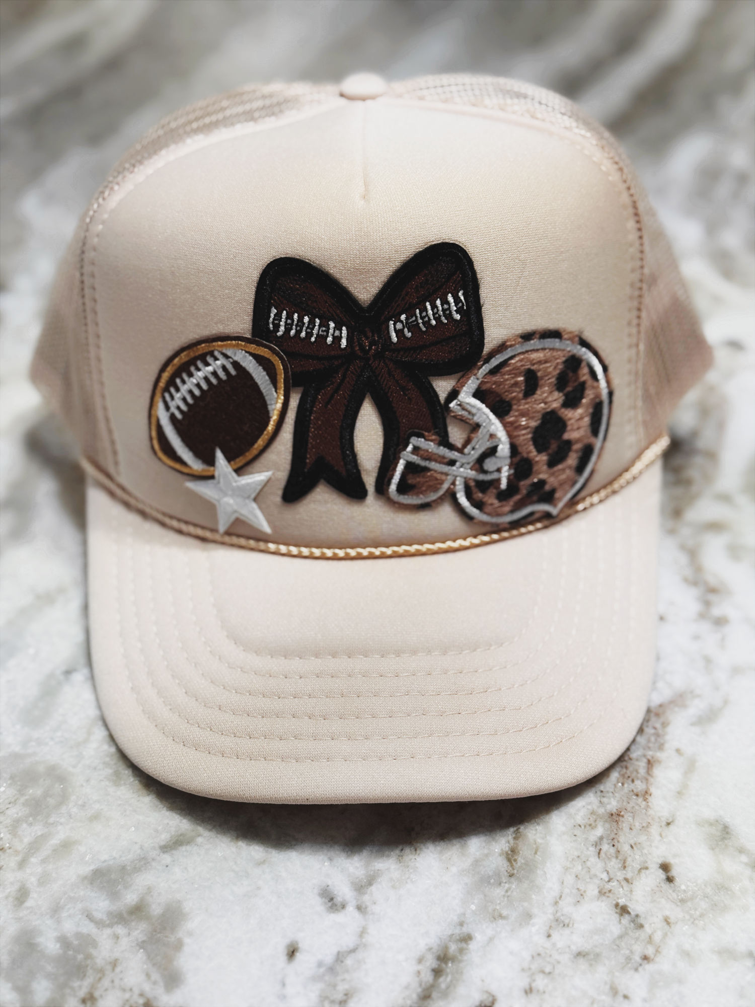 Beige cap with decorative patches on a marble surface