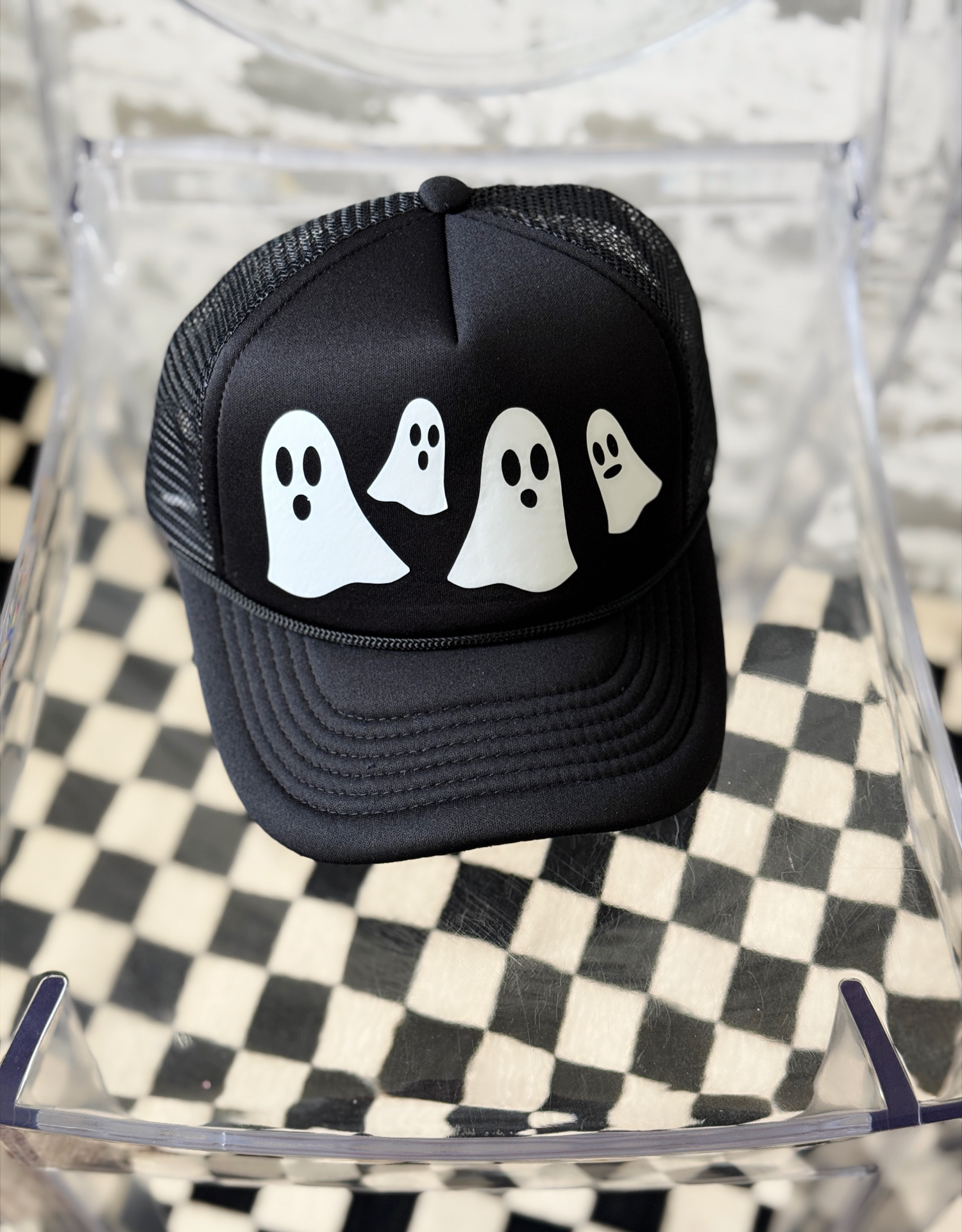 Black cap with white ghost designs on a checkered surface