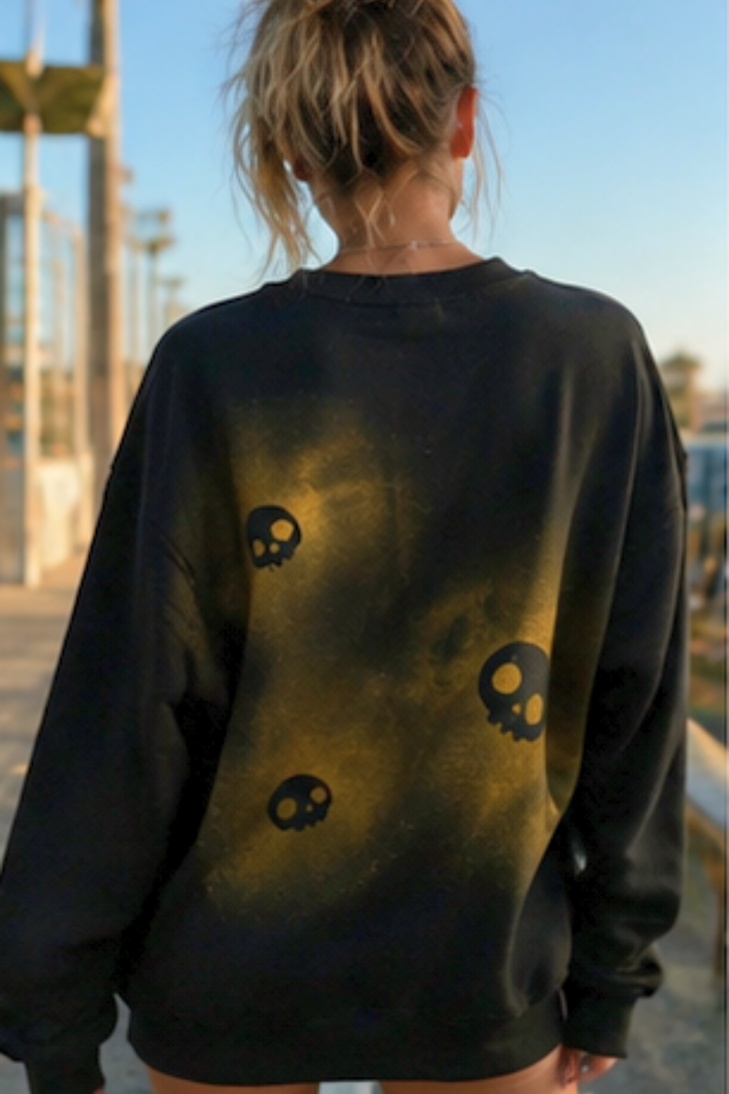 a black crewneck sweatshirt with a gold skeleton rib cage graphic and skull motifs,