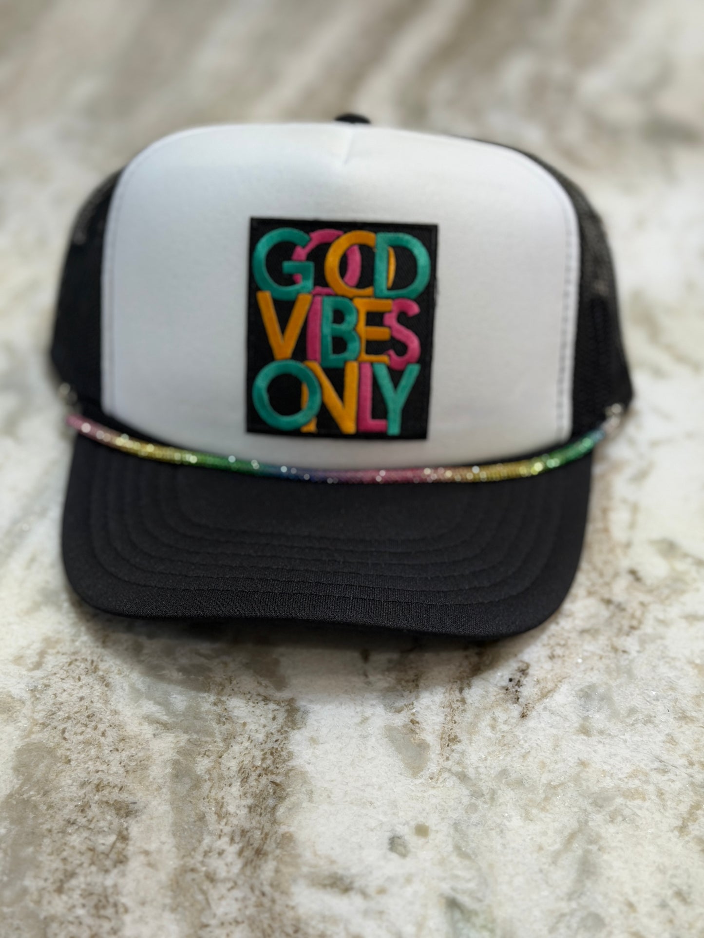 Trucker hat with 'Good Vibes Only' text on a marble surface
