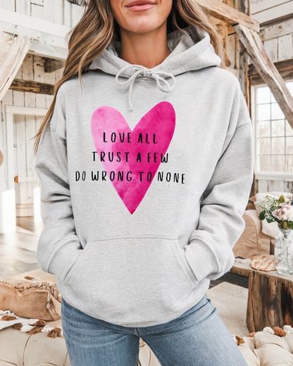 Person wearing a gray hoodie with a pink heart and text in a rustic indoor setting