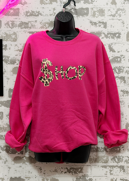 Pink sweatshirt with leopard print text on a textured wall background