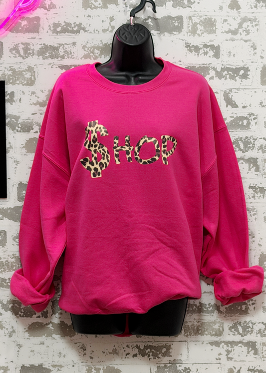 Pink sweatshirt with leopard print text on a textured wall background