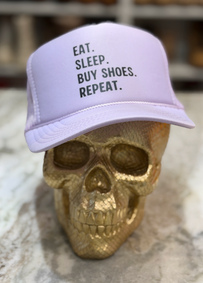 Light purple cap with 'Eat. Sleep. Buy Shoes. Repeat.' text on a gold skull.