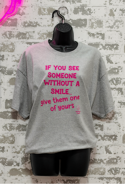 Gray t-shirt with pink text on a textured wall background
