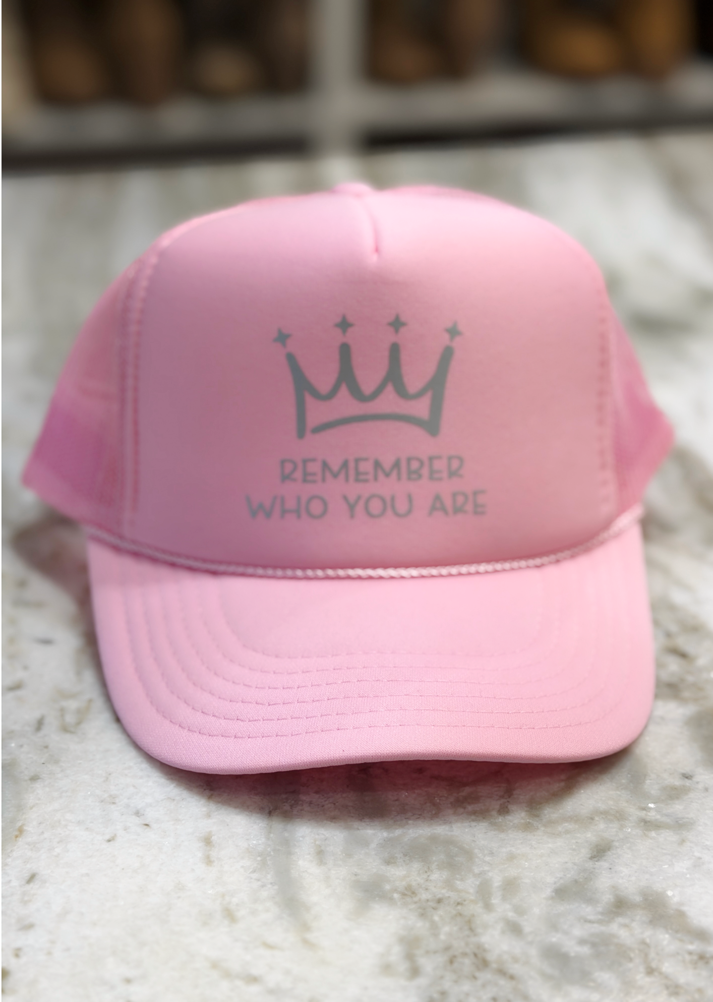 Pink cap with a crown and text design on a textured surface