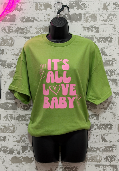 Green t-shirt with pink text 'IT'S ALL LOVE BABY' on a textured wall background