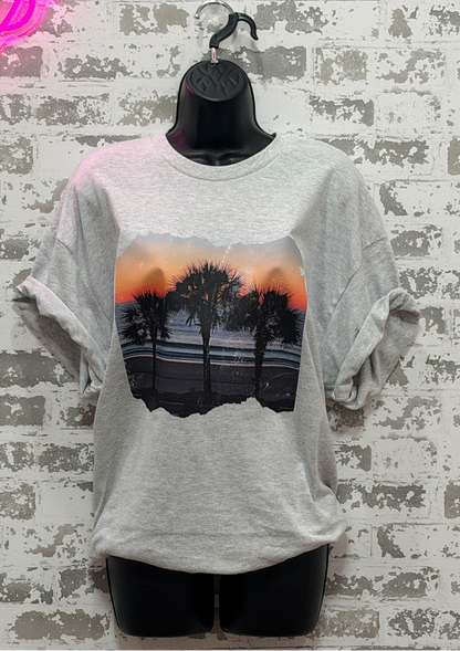 Gray t-shirt with a palm tree design on a textured wall background