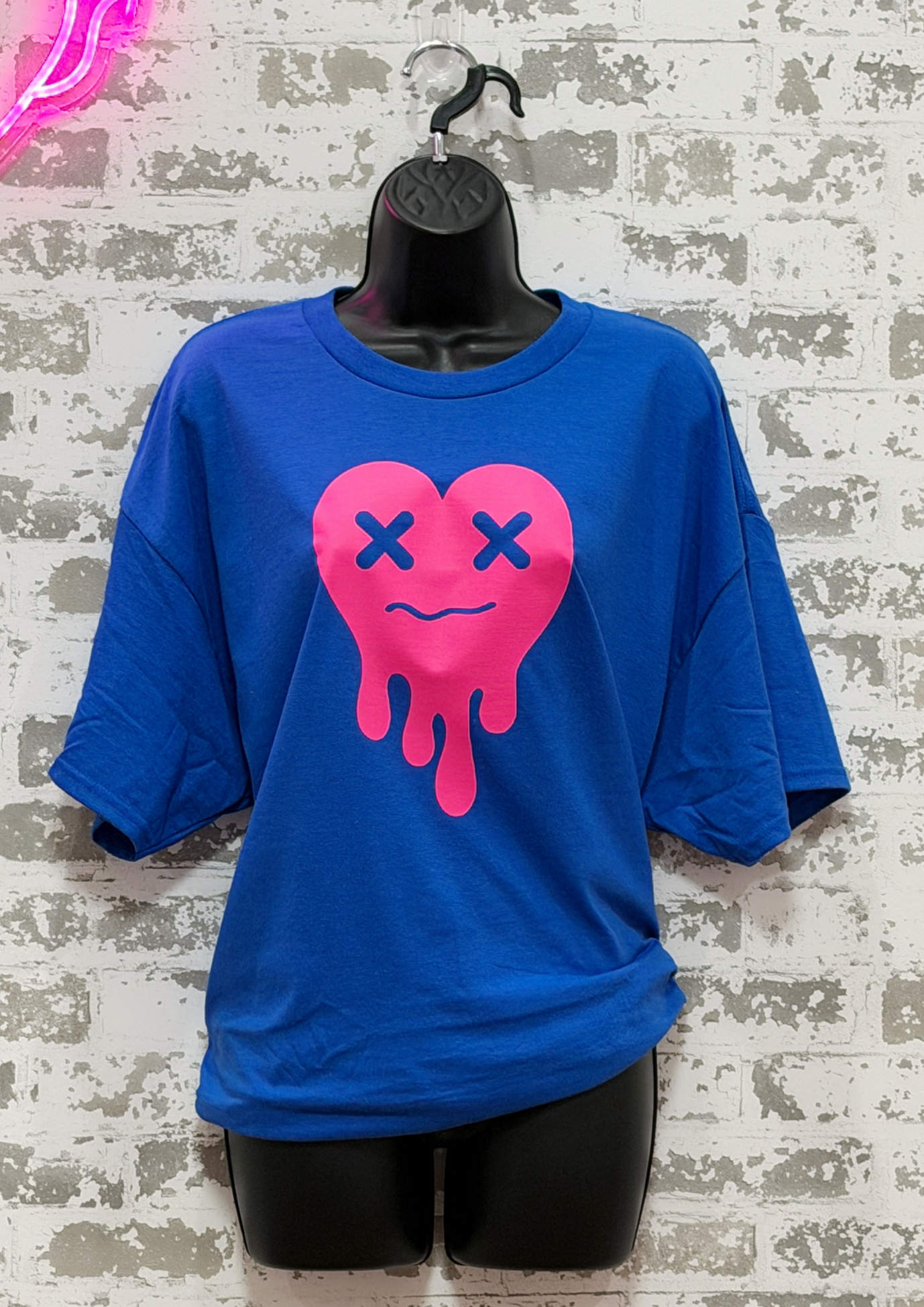 Blue t-shirt with a pink heart design on a textured wall background