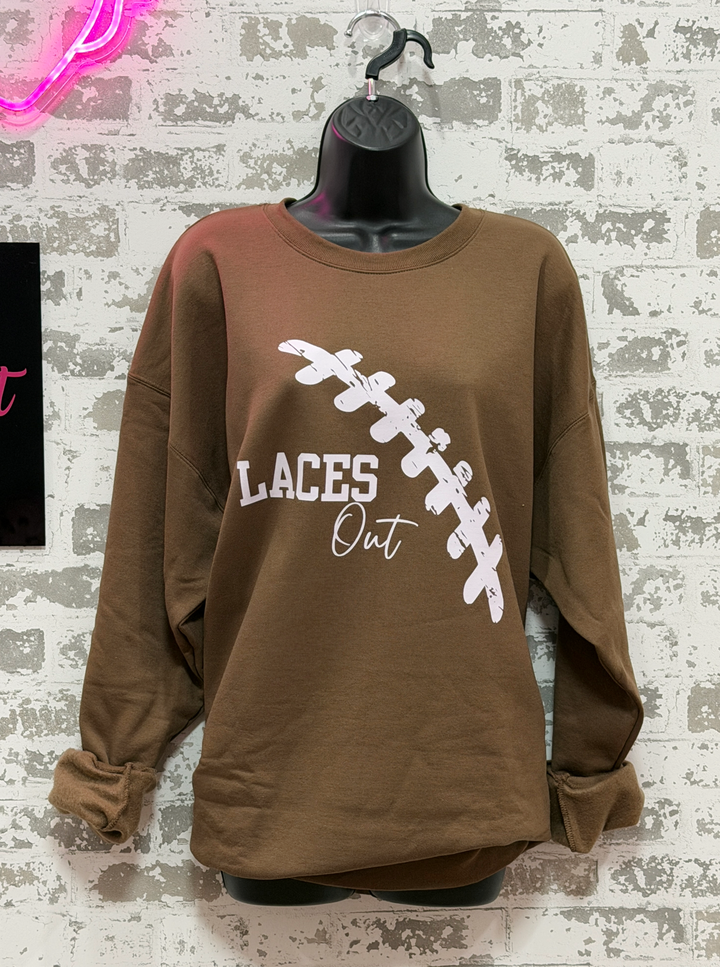  brown sweatshirt with light pink "Laces Out" football graphic 
