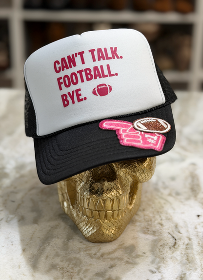 A black and white trucker hat with the text 'CAN'T TALK. FOOTBALL.BYE.
