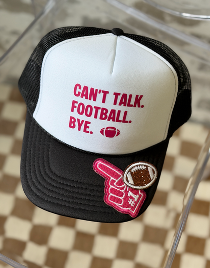A black and white trucker hat with the text 'CAN'T TALK. FOOTBALL. BYE.