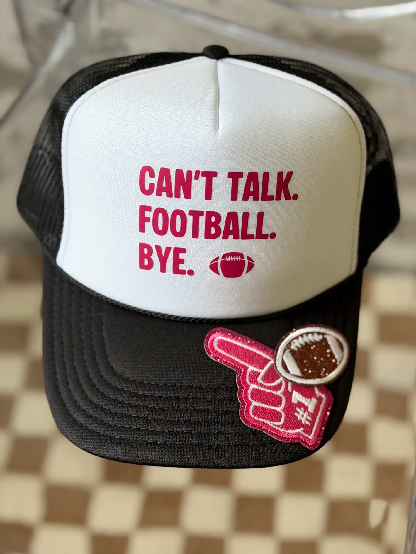 A black and white trucker hat with the text 'CAN'T TALK. FOOTBALL. BYE.