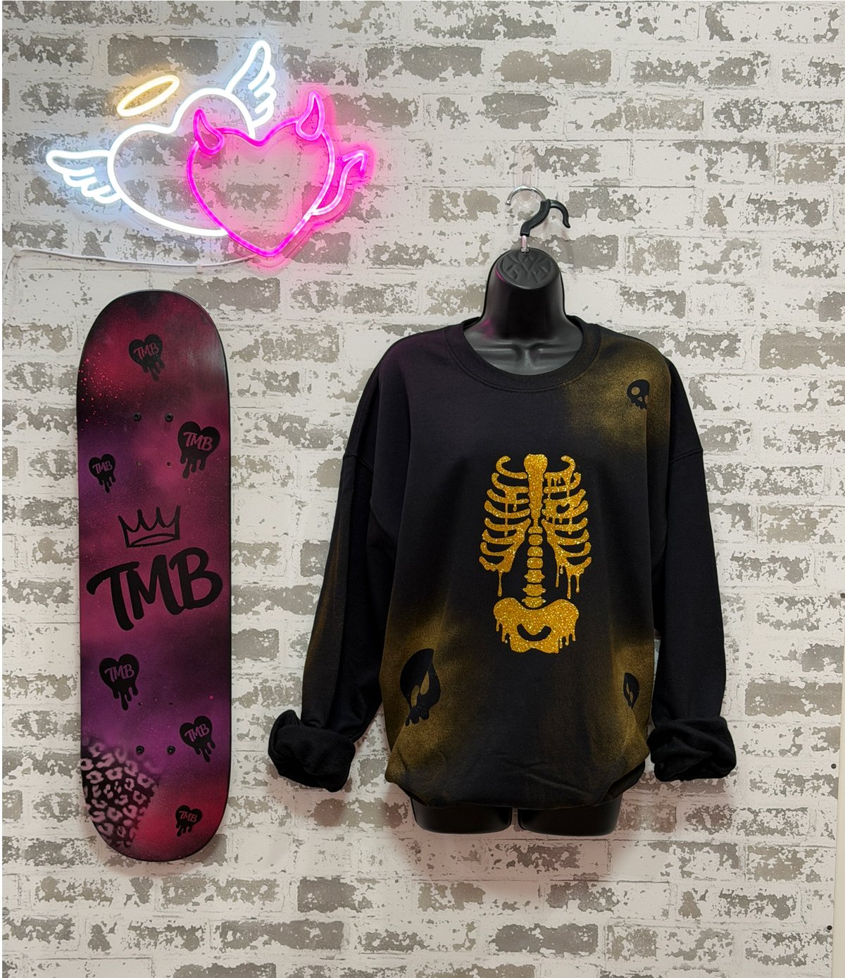 a black crewneck sweatshirt with a gold skeleton rib cage graphic and skull motifs,