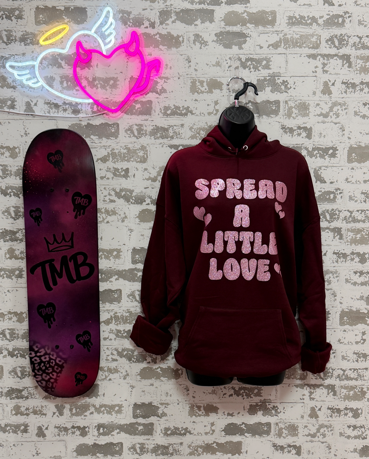  a maroon sweatshirt that says "Spread A Little Love" in a pink glitter graphic with hearts.