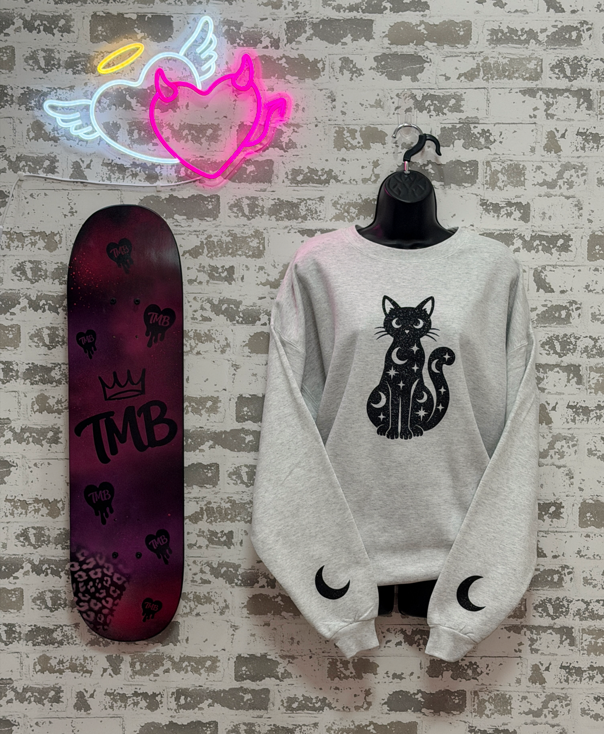 a light gray crewneck sweatshirt with a black cat and moon graphic,