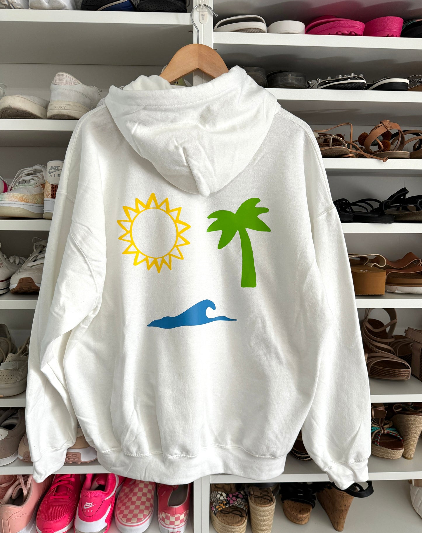 White hoodie with sun, palm, and wave graphic