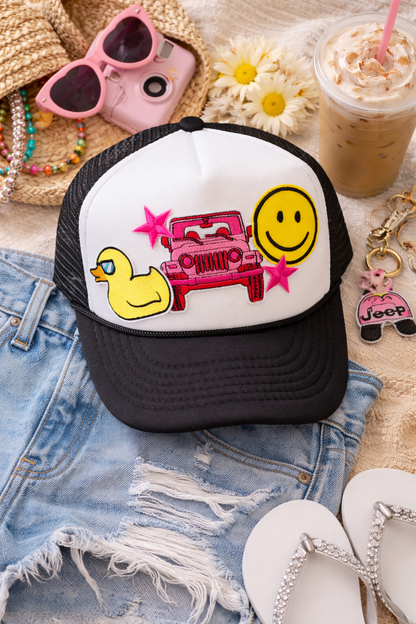 Trucker hat with jeep designs on a denim surface with sunglasses, flowers, and a drink.