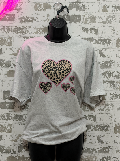 Gray t-shirt with leopard print heart designs on a textured wall background