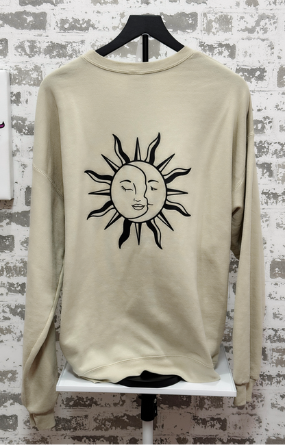 Beige sweatshirt with a sun and moon design on a textured white background