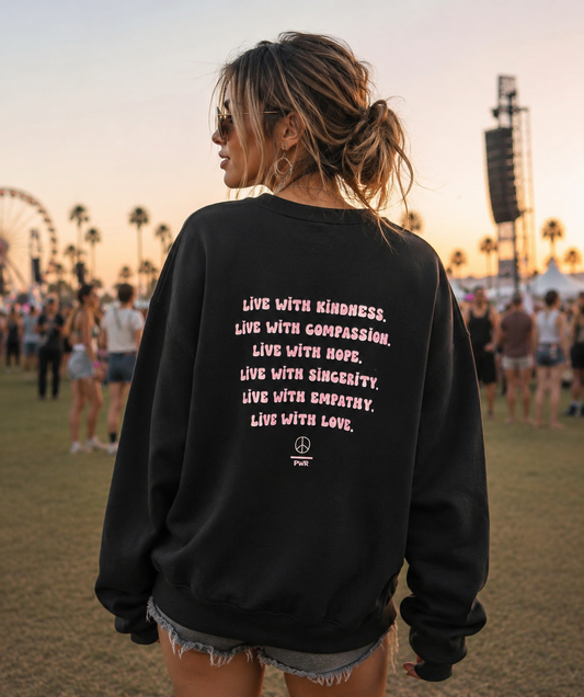 Person wearing a black sweatshirt with inspirational text at a festival.